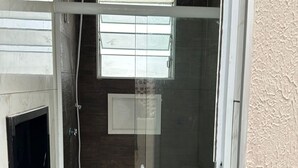 A modern bathroom with a glass-enclosed shower, a built-in toilet, and a window above the sink. - Moriah Pousada e  Hostel (Praia Grande)