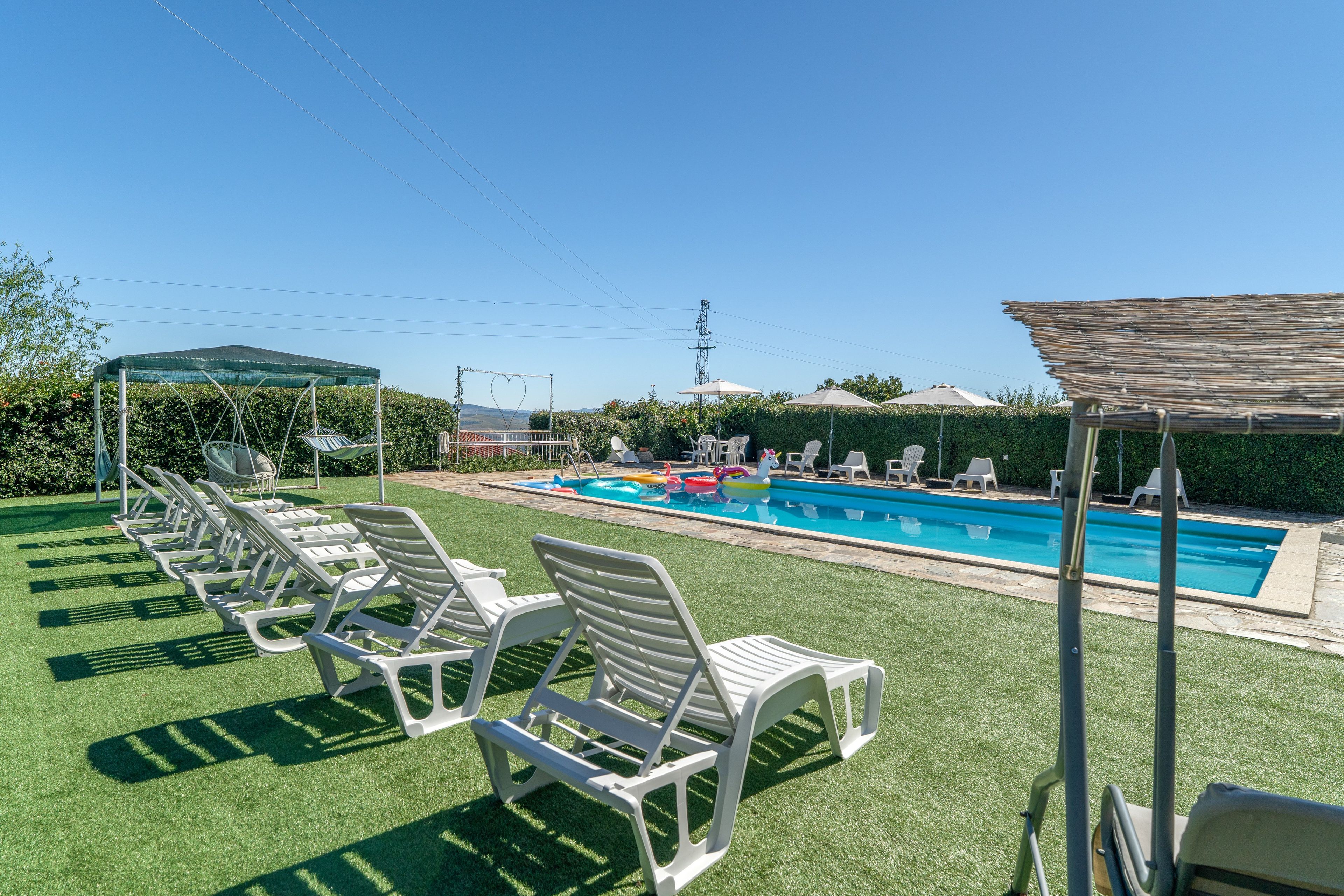 Un espace piscine avec des chaises longues et un coin salon abrité.