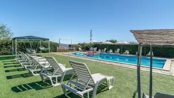 Un espace piscine avec des chaises longues et un coin salon abrité.