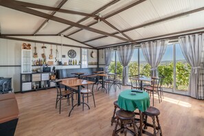 A spacious room with a high ceiling, wooden tables and chairs, a green tablecloth-covered table, and a view of the countryside through large windows. - Casa da Jesus with Mountain View, Wi-Fi, and Air Conditioning (Provesende)