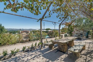 An outdoor seating area with stone tables and benches, surrounded by gravel and plants. - Casa da Jesus with Mountain View, Wi-Fi, and Air Conditioning (Provesende)