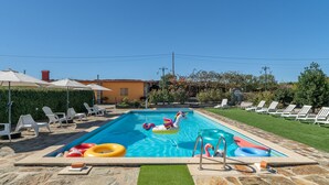 A swimming pool with lounge chairs and inflatable toys.