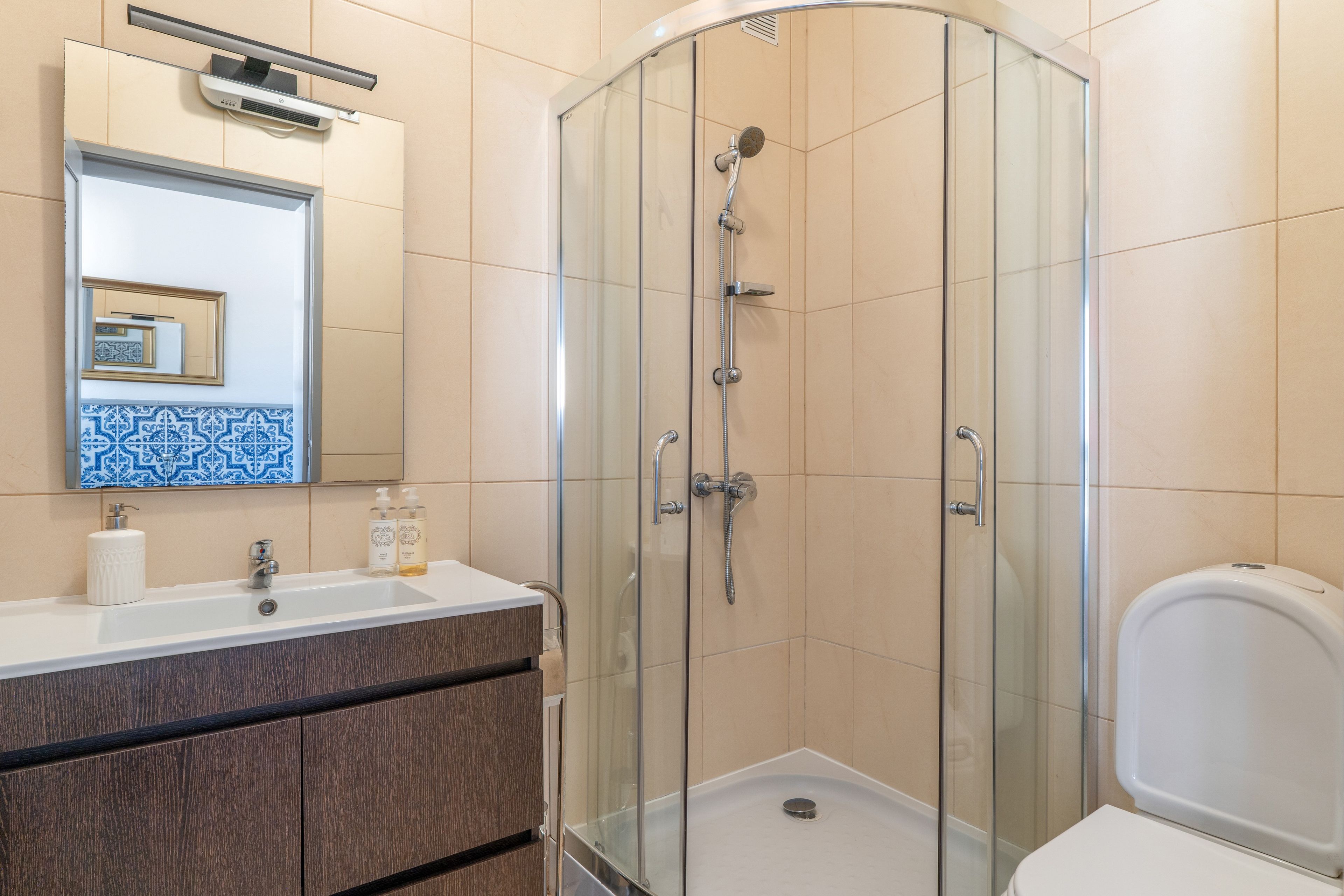 Ein modernes Badezimmer mit einer Duschkabine, einem Waschbecken mit Spiegel darüber und einer Toilette.