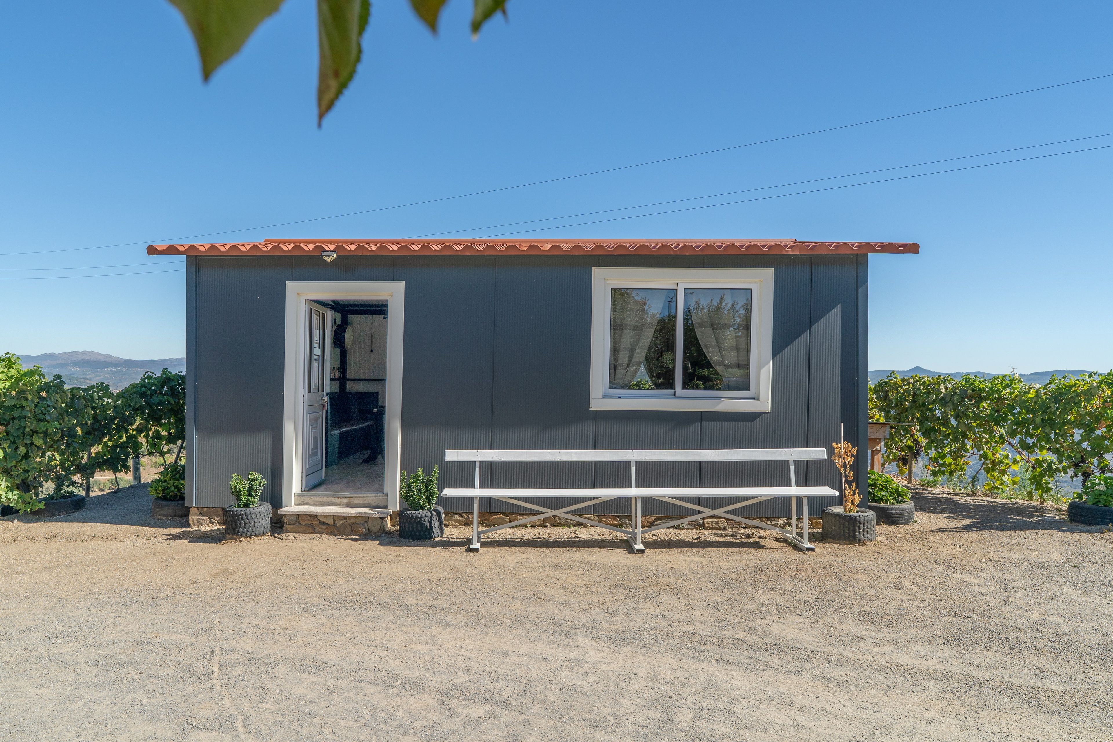 Un petit bâtiment avec un banc devant, une porte et des fenêtres.