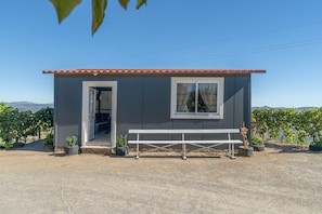 Un petit bâtiment avec un banc devant, une porte et des fenêtres.