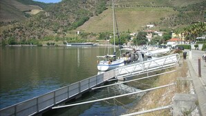 A riverside dock with boats, a bridge, and a hilly landscape in the background.