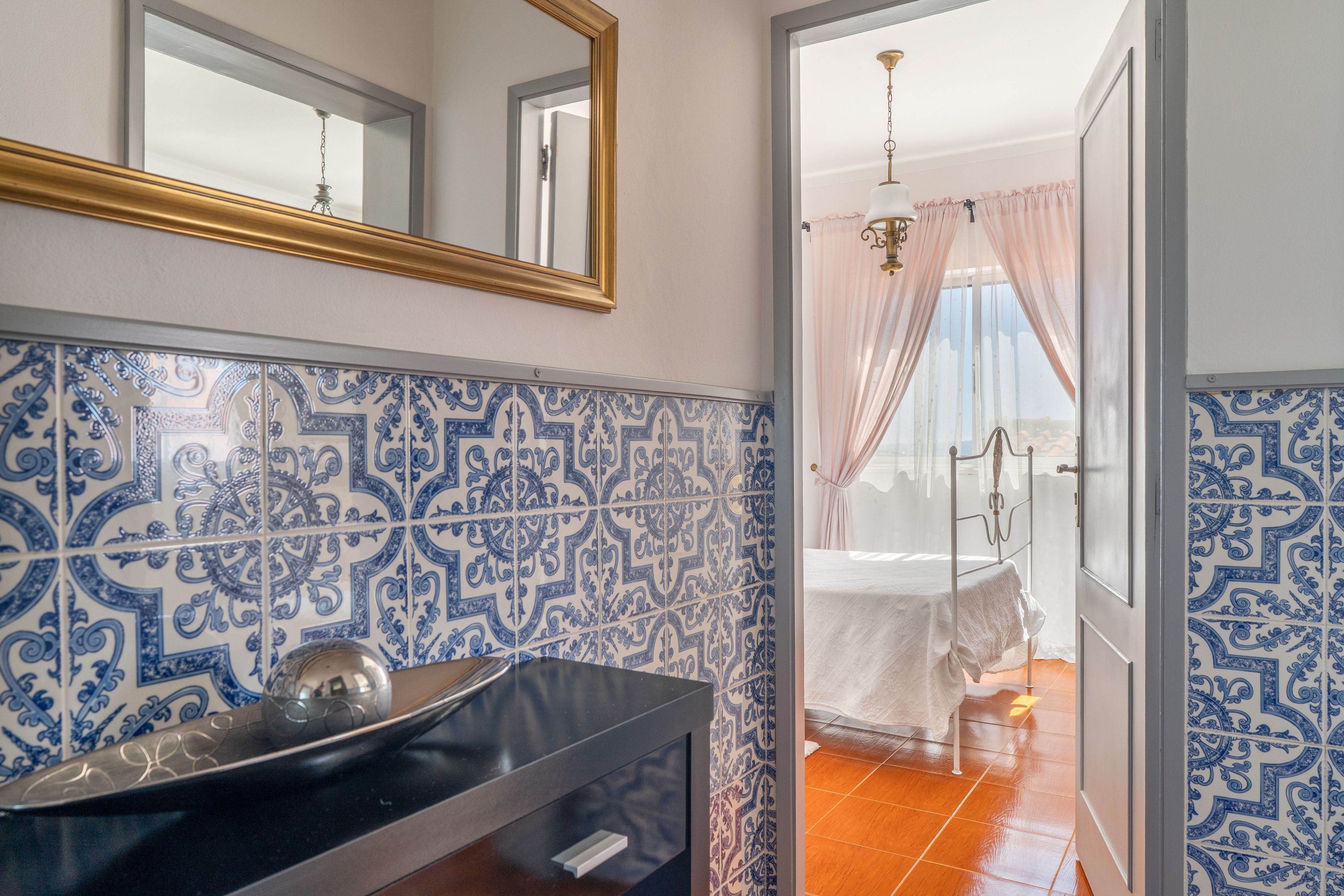 A bathroom with a sink, mirror, and patterned tiles.