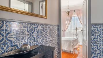 A bathroom with a sink, mirror, and patterned tiles.