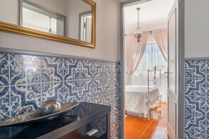 Une salle de bain avec un lavabo, un miroir et des carreaux décorés.