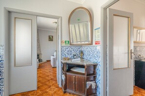 Un pasillo con un armario de madera, un espejo y un revestimiento de baldosas.