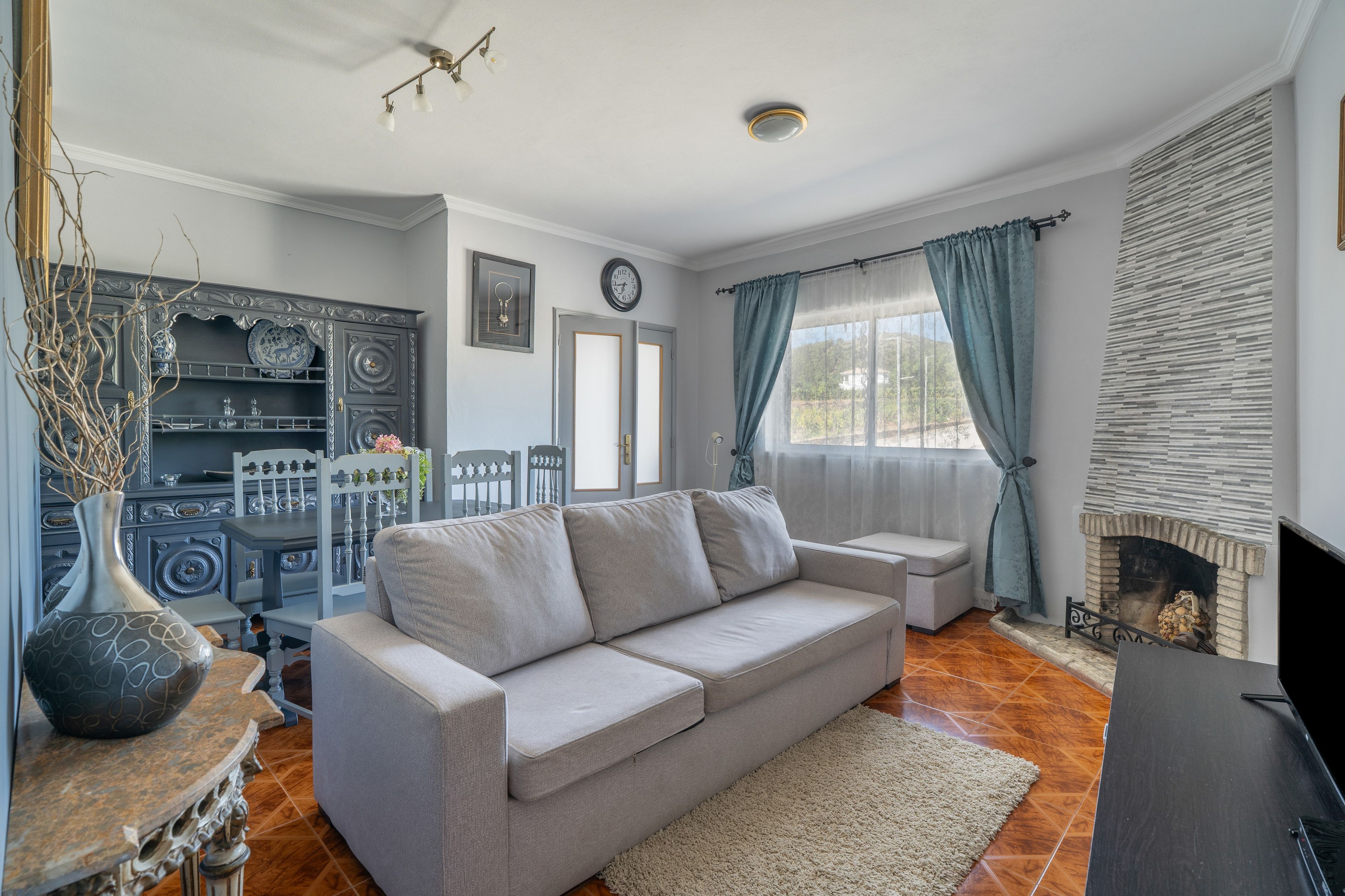 A living room with a sofa, a fireplace, and a decorative cabinet.