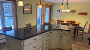 Una cucina con piano di lavoro in granito nero, mobili bianchi e un tavolo da pranzo in legno con sedie.