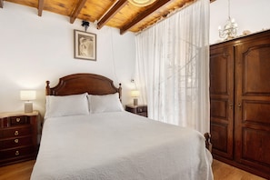 A bedroom with a wooden bed, nightstands, a wardrobe, and a chandelier.