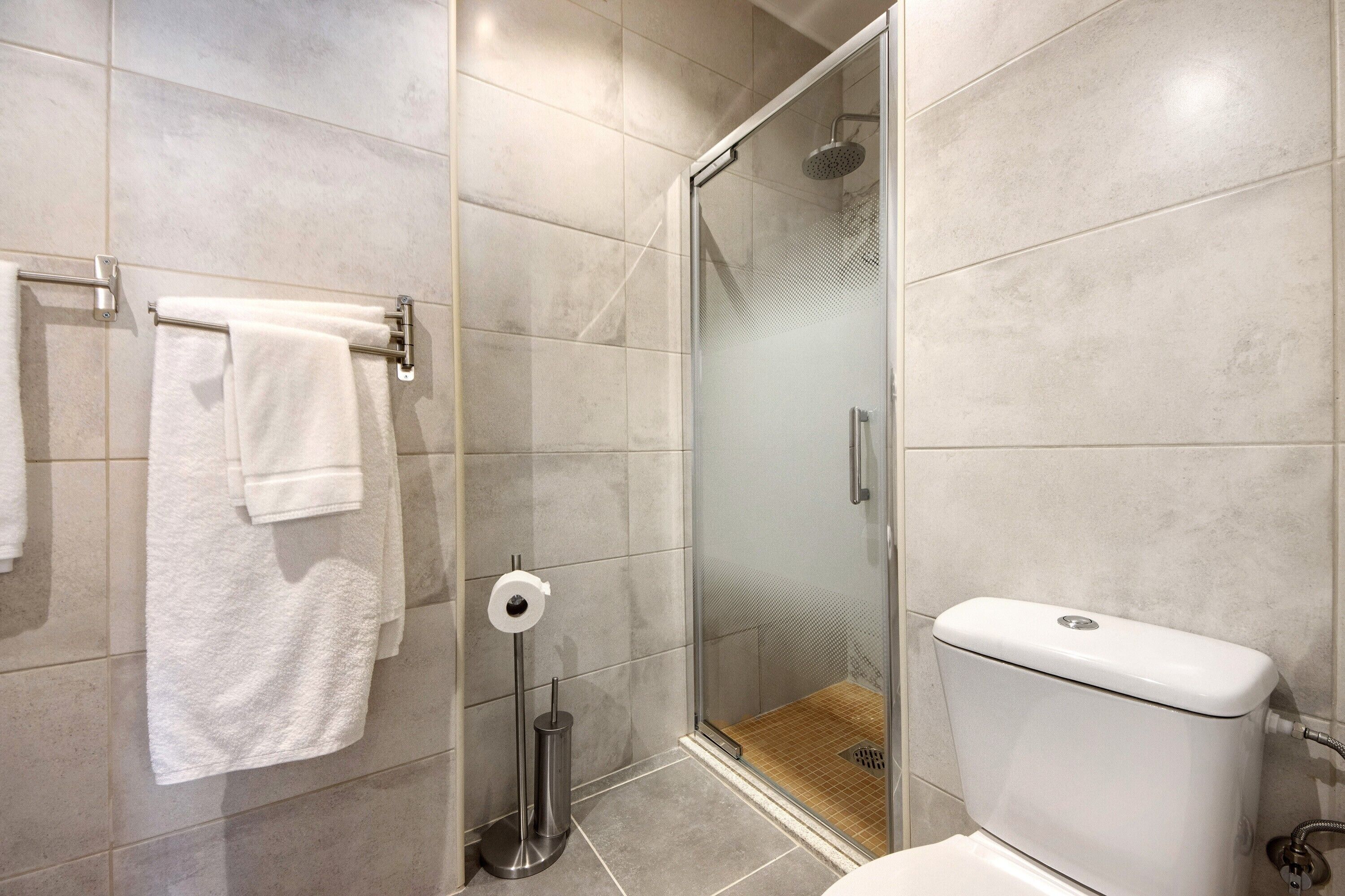 Une salle de bain avec une douche à parois de verre, des toilettes et un porte-serviettes avec des serviettes blanches.