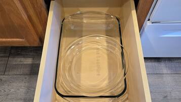 Un plat de cuisson en verre transparent, rangé dans un tiroir en bois.