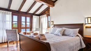 Une chambre avec un lit en bois, une chaise, une table et une vue sur l’extérieur.