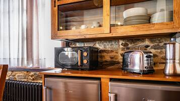 Een keuken met een stenen muur, een magnetron, een broodrooster en een koffiezetapparaat.