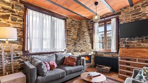 Un salon chaleureux avec un mur en pierre, une cheminée, un canapé, une table basse et un téléviseur.
