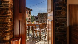 Une terrasse extérieure avec une table et des chaises, un sol en pierre et une vue sur la rue.