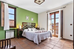 A bedroom with a bed, a nightstand, a chair, a window, and a door.