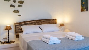 A bed with white linens, two bedside lamps, and a wall with scattered rocks.
