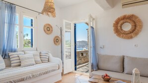 A room with a sofa, a table with a bowl and a lantern, and a view through an open door.