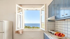 A kitchen with a view of the sea, a stove, and a bowl of fruit on the counter. - Apartment 'Suite No 4' with Sea View, Wi-Fi and Air Conditioning (Kini)