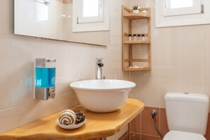 A bathroom with a white sink, a towel, a shelf with toiletries, and a toilet. - Apartment 'Suite No 4' with Sea View, Wi-Fi and Air Conditioning (Kini)