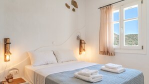 A hotel room with a bed, a nightstand, a lamp, a window with a view, and a curtain. - Apartment 'Suite No 4' with Sea View, Wi-Fi and Air Conditioning (Kini)