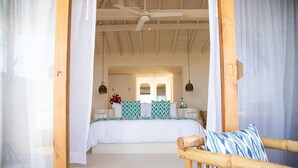 A bedroom with a bed, a wooden chair, and a ceiling fan.