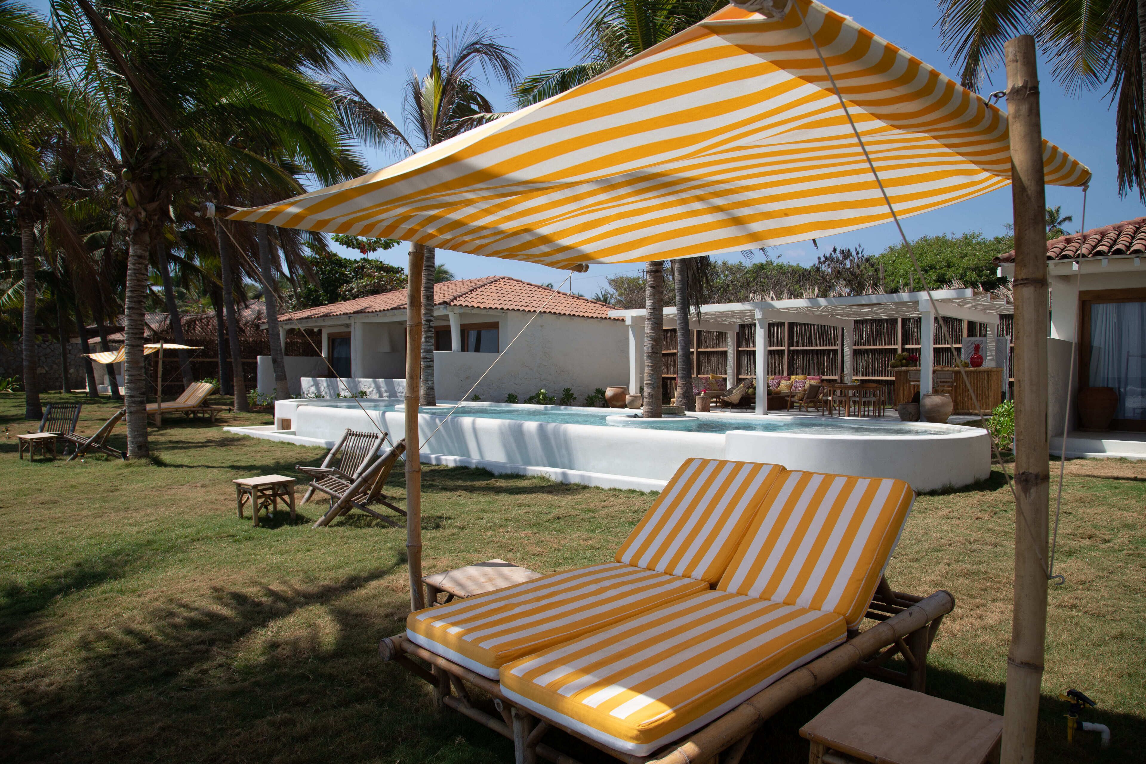 A poolside area with striped umbrellas, lounge chairs, and a pool.