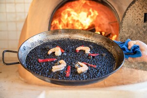 Una sartén con camarones y pimientos rojos sobre una parrilla.
