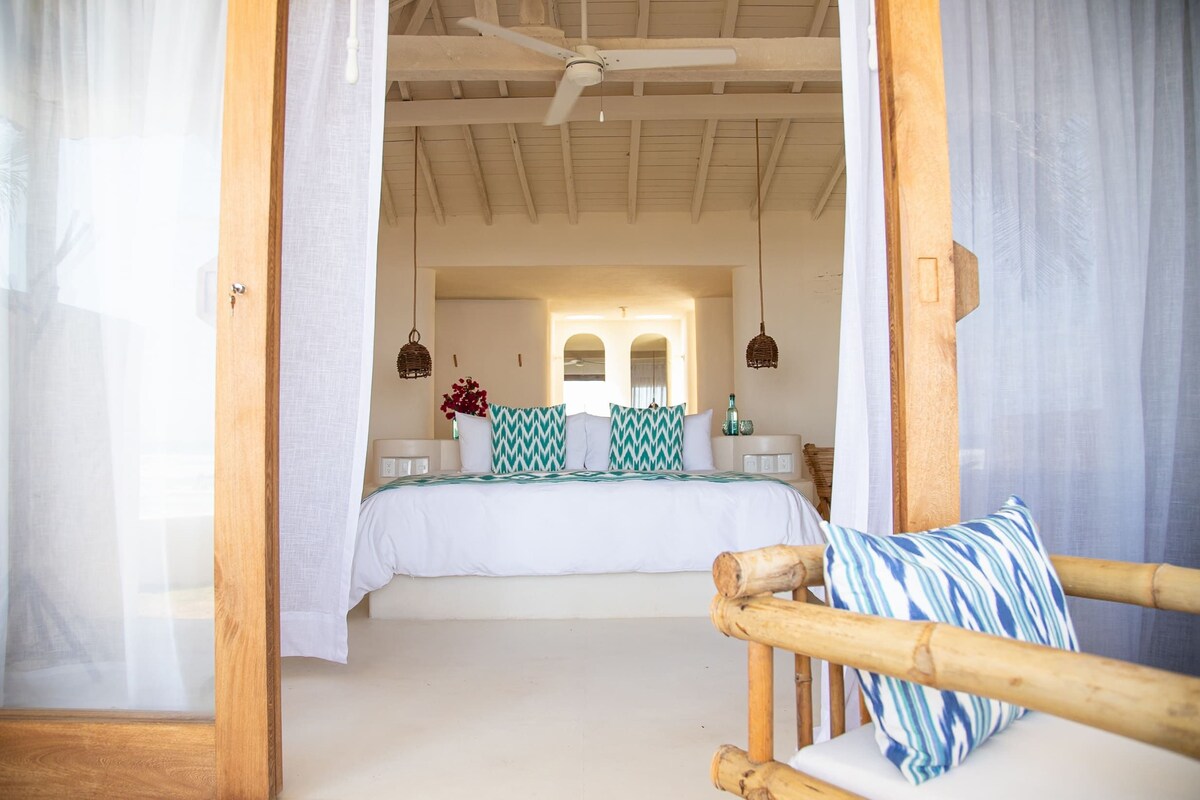 A bedroom with a bed, a wooden chair, and a ceiling fan.