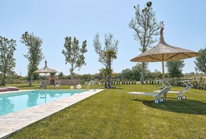 A swimming pool with lounge chairs and umbrellas, surrounded by a well-maintained lawn and trees. - Apartment 'Ca' Marano Lagoon' with Shared Pool, Wi-Fi and Air Conditioning (Località Bevazzana)
