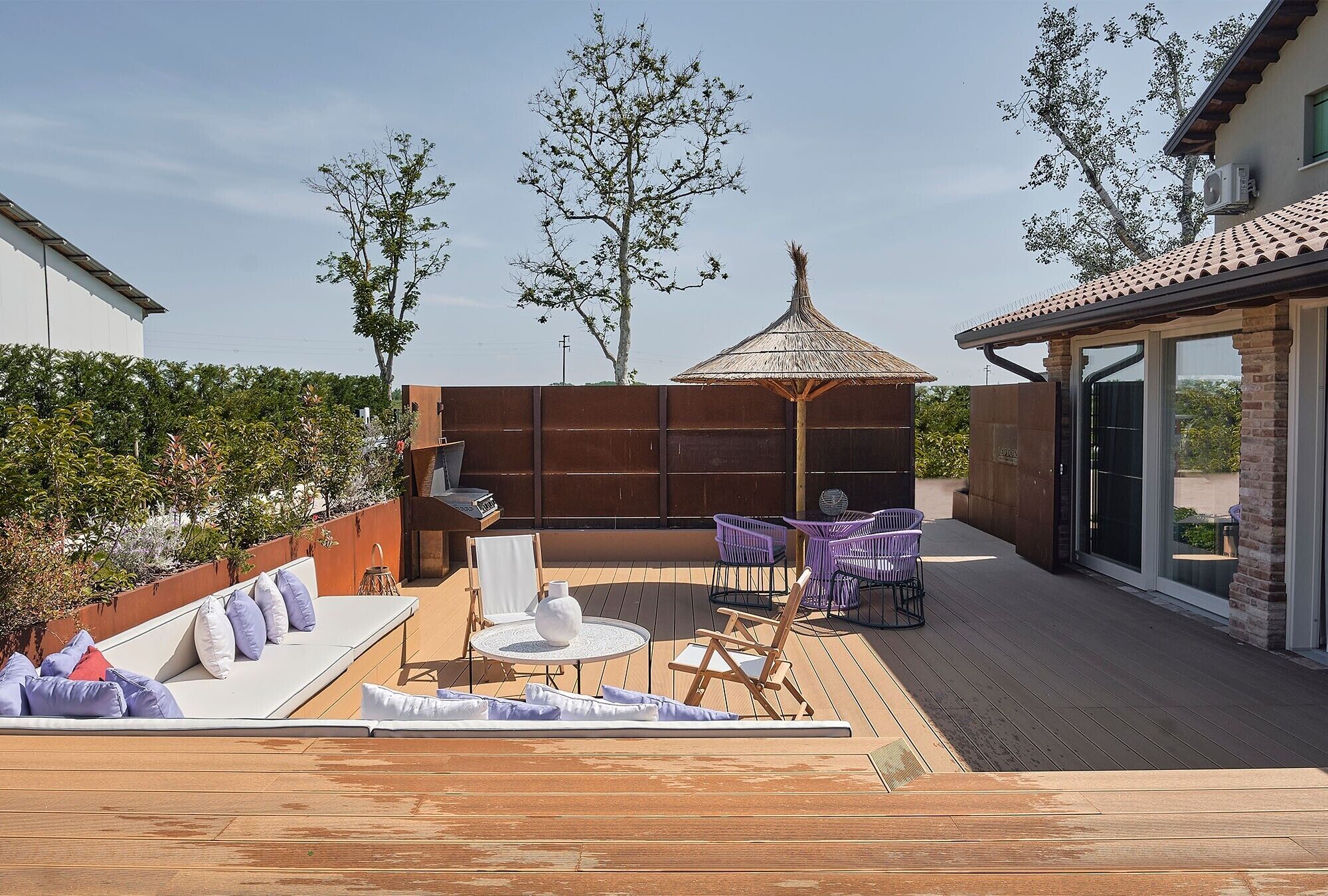 A patio with a dining area, a lounge with cushions, and a pergola.