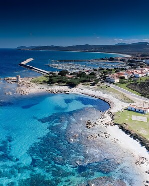 An aerial view of a coastal area with clear blue waters, a marina, and residential buildings. - Holiday Home 'Bouganville' with Mountain View, Private Garden and Air Conditioning (Posada)