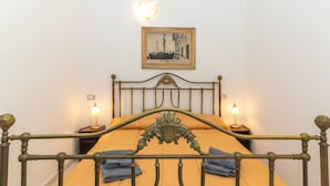 Un lit doté d’une tête de lit décorative, deux lampes de chevet, un tableau encadré accroché au mur et une petite table avec une lampe.