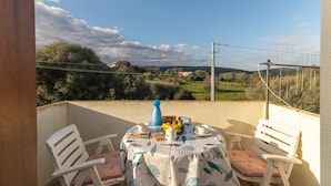 Un balcon avec une table dressée pour le petit-déjeuner, des chaises et une vue sur la campagne.