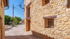 Una calle estrecha con edificios de piedra, una puerta a la vista y una ventana con barrotes.