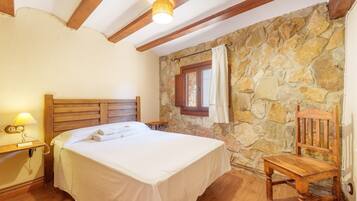 Ein Schlafzimmer mit Steinwand, Holzbettgestell und Holzstuhl.