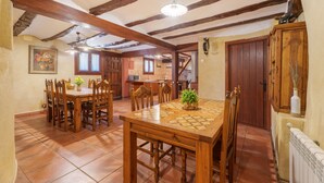 Un comedor con muebles de madera, suelo de baldosas y techo con vigas a la vista.