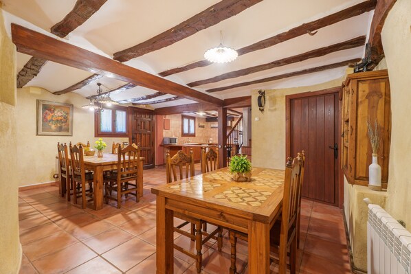 Un espace repas avec des meubles en bois, un sol carrelé et un plafond avec des poutres apparentes.