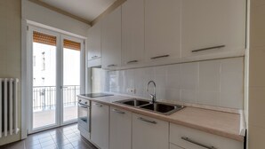 Une cuisine avec des meubles blancs, un évier à deux bacs et une vue sur l’extérieur.