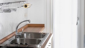 A kitchen with a gas stove, stainless steel sink, and wooden cabinets. - Holiday apartment mit Balkon (Jesolo)