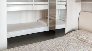 A bedroom with a bunk bed, a large mirror, and a floral-patterned bedspread. - Holiday apartment mit Balkon (Jesolo)