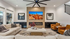 A modern living room with a fireplace, a large TV, and a staircase. - Pecan Valley Resort|Private Pool w/Slide, Smart TV's, & Pickleball Court (Hurricane)