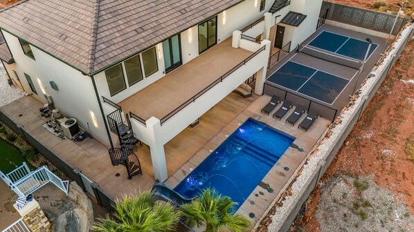 A two-story house with a swimming pool, outdoor seating, and a tennis court. - Pecan Valley Resort|Private Pool w/Slide, Smart TV's, & Pickleball Court (Hurricane)