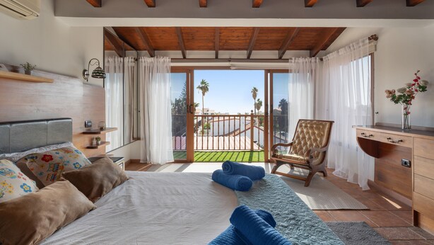Un dormitorio con cama, una silla, un escritorio y un balcón con vistas.