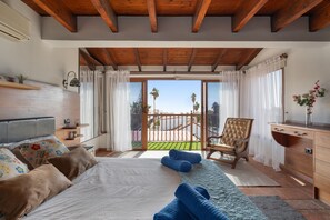 Une chambre à coucher avec un lit, une chaise, un bureau et un balcon offrant une vue.