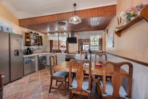 Une cuisine avec des meubles de rangement en bois, une table à manger, des chaises, un lave-linge et un réfrigérateur.